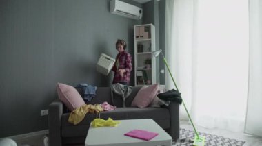 Kadın sepetten dağınık eşyaları topluyor.