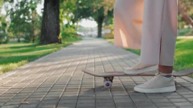 Kaykaycı elinde kaykayla durur ve onu iterdi.