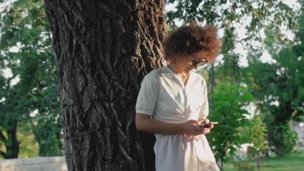 Curly woman is Using Mobile Phone In The Public Park. — Stock Video