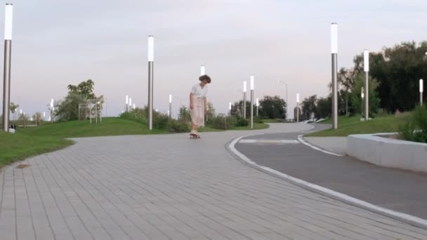 Fiatal női gördeszkás próbál egy trükk, és elesik a parkban — Stock videók