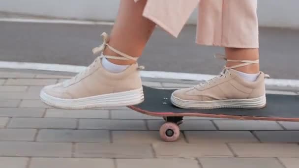 Красивые ноги женщины в бежевых кроссовках катаются на скейтборде — стоковое видео