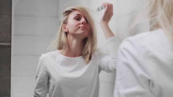 Beautiful Woman looking at the mirror and touching her face — Stock Video