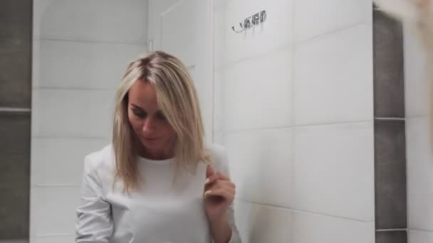 Vrouw aanbrengen lotion en kijken in spiegel genieten van natuurlijke schoonheid en gezond — Stockvideo
