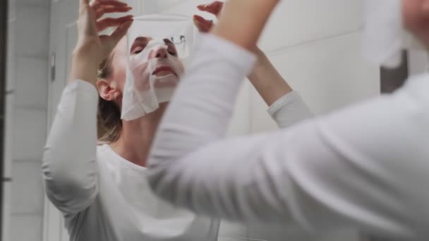 Kvinna tar bort mask på hennes ansikte ser i spegeln — Stockvideo