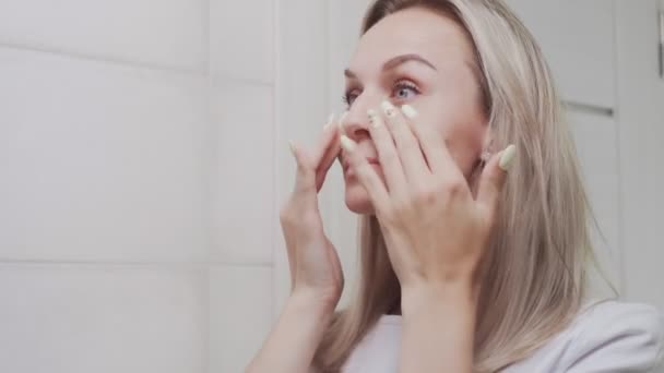 Primer plano de mujer joven elegante mirando el espejo y tocando su cara en el baño — Vídeo de stock