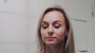 Gözlerinin altına krem süren ve kameraya bakan kadın.