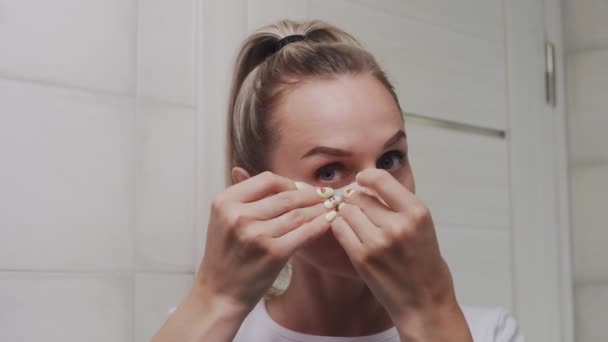 Aproape de femeie pune tampoane de colagen sub ochii ei și se uită la camera foto — Videoclip de stoc