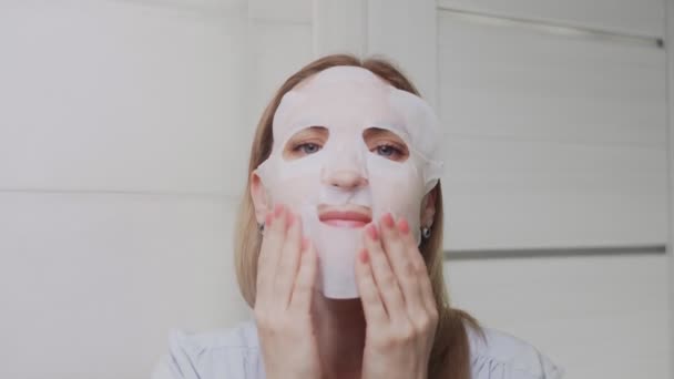 Крупный план взрослой женщины, надевающей маску на лицо и смотрящей в камеру — стоковое видео
