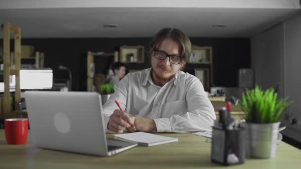 젊은 관리자는 사무실에서 혼자 책상에 앉아서 글을 쓰고 있습니다 — 비디오