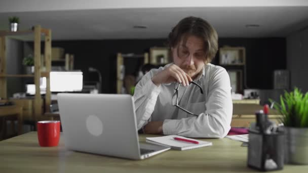 Менеджер работает в офисе писать сидя за столом — стоковое видео