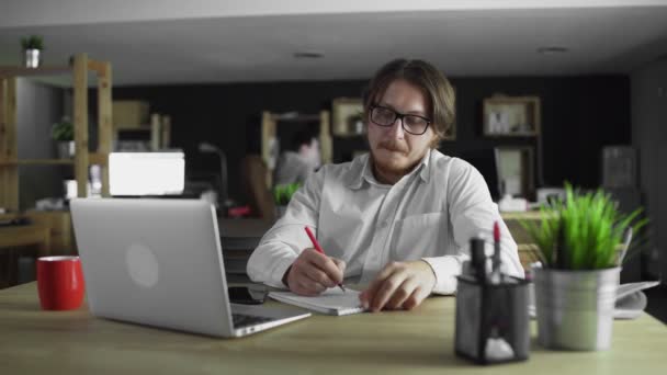 Az üzletember irodai munkát végez, és egyedül ül az asztalnál. — Stock videók