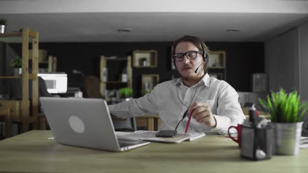 Junger Manager mit Kopfhörer arbeitet im Büro — Stockvideo