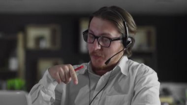 Kulaklıklı genç yönetici ofiste çalışıyor.