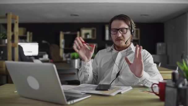 Менеджер в наушниках работает на ноутбуке в офисе — стоковое видео