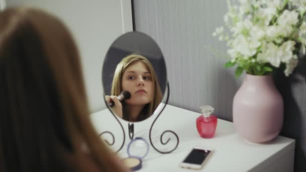 Молода красива жінка тримає пензлик наносить рум'яна пудра і розмовляє на смартфон — стокове відео