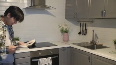 Gazeteli Asyalı adam mutfakta kurabiye yiyor..