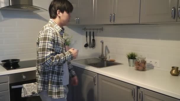 Азиатский мужчина берет печенье и пьет кофе дома на кухне . — стоковое видео