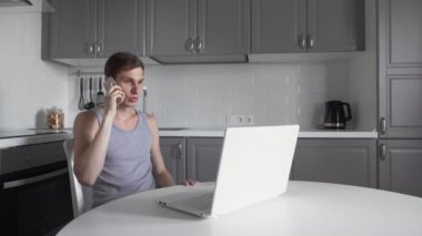 Freelancer telefonda konuşuyor ve mutfakta defter üzerinde çalışıyor..