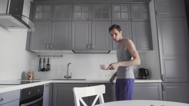 Jovem tomando café da manhã na cozinha . — Vídeo de Stock