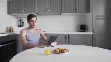 Adam mutfakta tablet bilgisayarında sohbet ediyor.