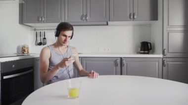 Genç adam masada oturuyor ve kulaklıkla müzik dinliyor.