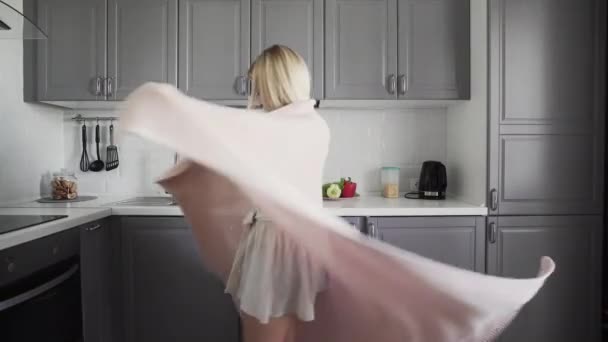 Chica alegre girando en un cuadros y sonriendo en la cocina por la mañana — Vídeo de stock