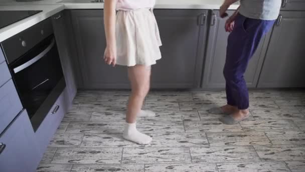 Low angle shot aantrekkelijk jong vrolijk paar veel plezier dansen tijdens het koken in de keuken thuis — Stockvideo
