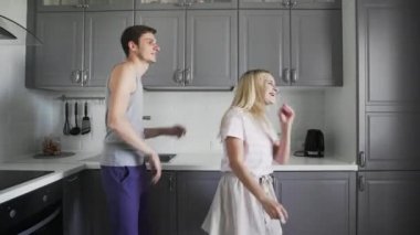 Evdeki mutfakta birlikte gülüp, eğlenip, dans eden eğlenceli genç insanlar.