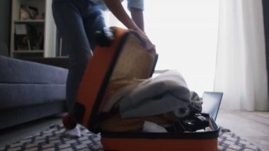 Seyahat eden kadın otel odasında bavulunu boşaltıyor.