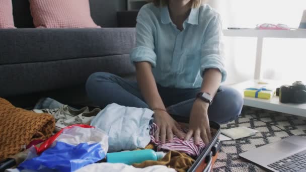 Chica cuidadosamente pone la ropa de vacaciones en una maleta — Vídeo de stock