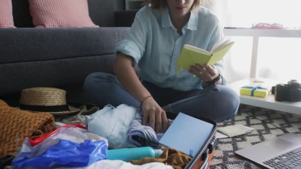 Jovem com um caderno nas mãos verifica a lista de roupas para férias — Vídeo de Stock