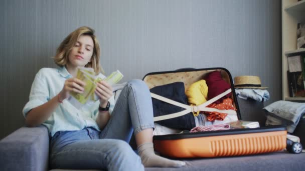 Счастливая женщина считает деньги и думает о своем будущем отпуске — стоковое видео