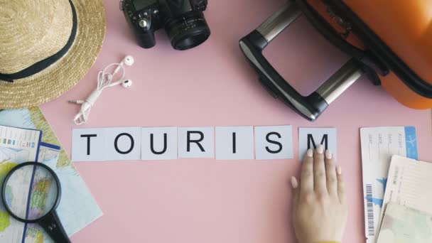 Top vue mains posées sur le bureau rose mot TOURISME — Video