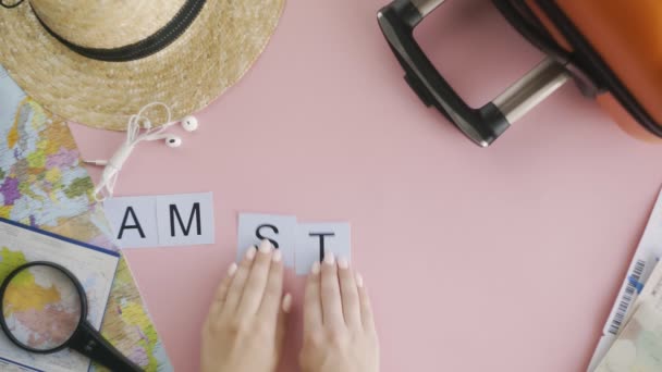 Manos de vista superior que ponen en la palabra escritorio rosa AMSTERDAM — Vídeo de stock