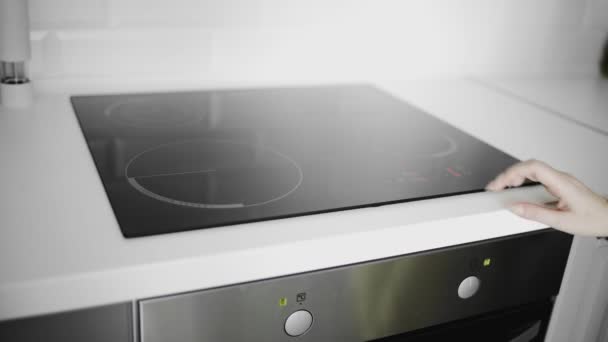 Gros plan d'une main féminine allumée sur une cuisinière à induction — Video