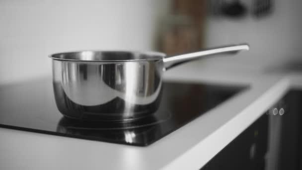 Woman takes off saucepan from induction cooker — Stock Video