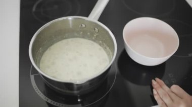 Süt aşçılı yulaf ezmesi ve mutfakta metal bir tencerede kaynatma.