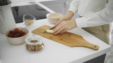 Kız mutfakta muz keserek temizledi.