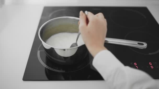 De koemelk kookt in een pan. Vrouw roert melk in steelpan — Stockvideo