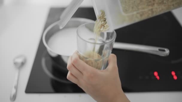 Havermout met melk koks en kookt in een metalen pan op het fornuis — Stockvideo