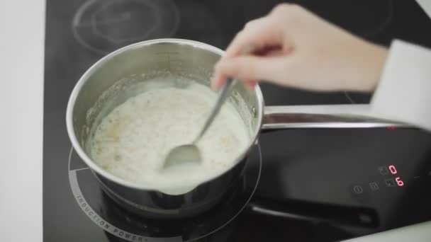 Овсянка с молоком поваров и кипит в металлической кастрюле на кухне плиты — стоковое видео