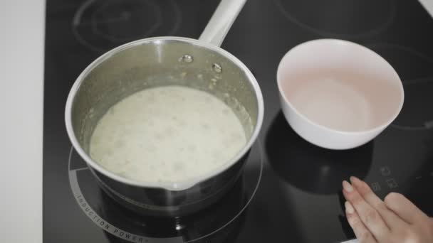 Oatmeal with milk cooks and boils in a metal saucepan on the kitchen stove — Stock Footage Oatmeal with milk cooks and boils in a metal saucepan on the kitchen stove Stock Footage