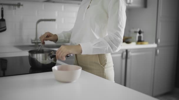 Haferflocken kochen, eine Frau gießt gekochten Haferbrei in Teller, Nahaufnahme, Frühstück — Stockvideo