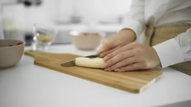 Close up de menina cortada banana limpa na cozinha — Vídeo de Stock