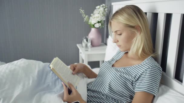 Kvinna i nattkalsonger läser bok innan du sover — Stockvideo