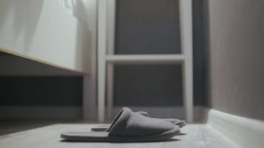 Yataktan kalkan kadın, gri terliklerini giy.