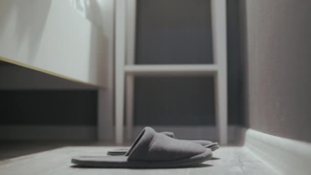 Vrouw die uit bed stapt, grijze pantoffels aantrekt — Stockvideo