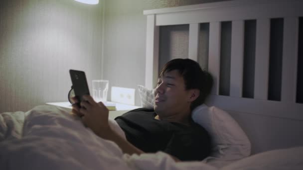 Jovem asiático homem com tablet computador deitado na cama — Vídeo de Stock
