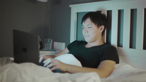Młody Azji człowiek za pomocą a Laptop późno w nocy w łóżko — Wideo stockowe