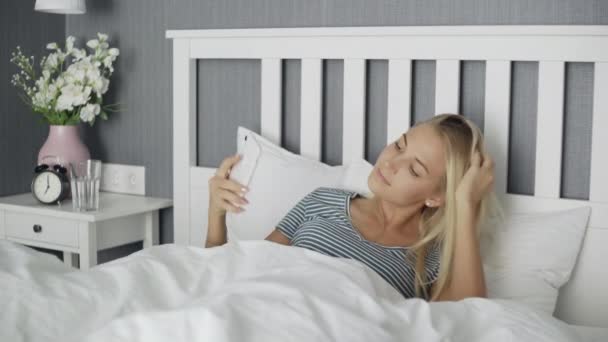 Sorrindo feliz bela jovem deitada na cama no quarto confortável e tirando fotos Selfie — Vídeo de Stock